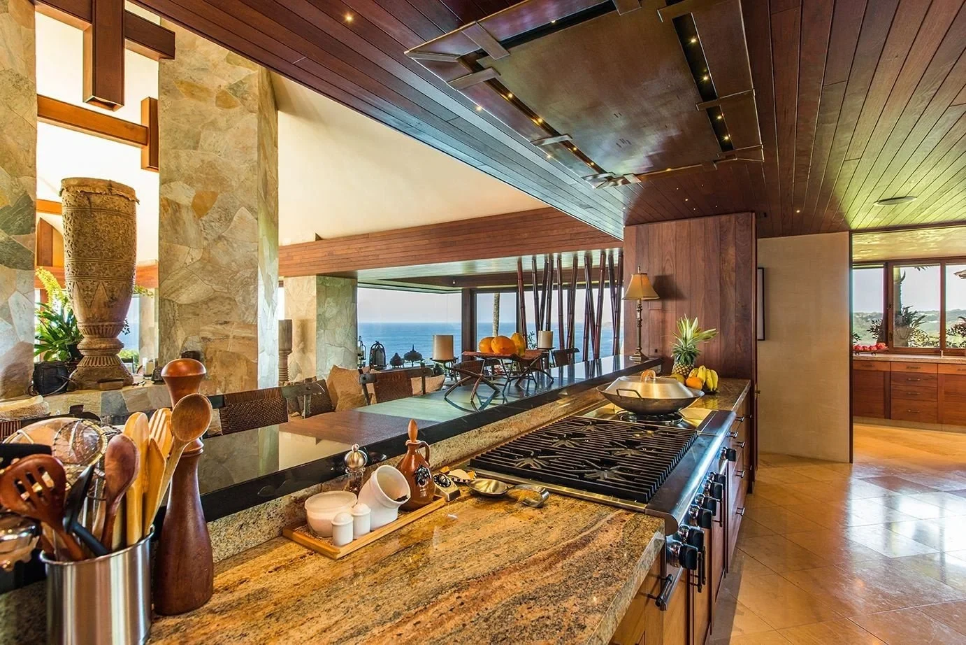 Open island kitchen with stone counters looking out to the ocean